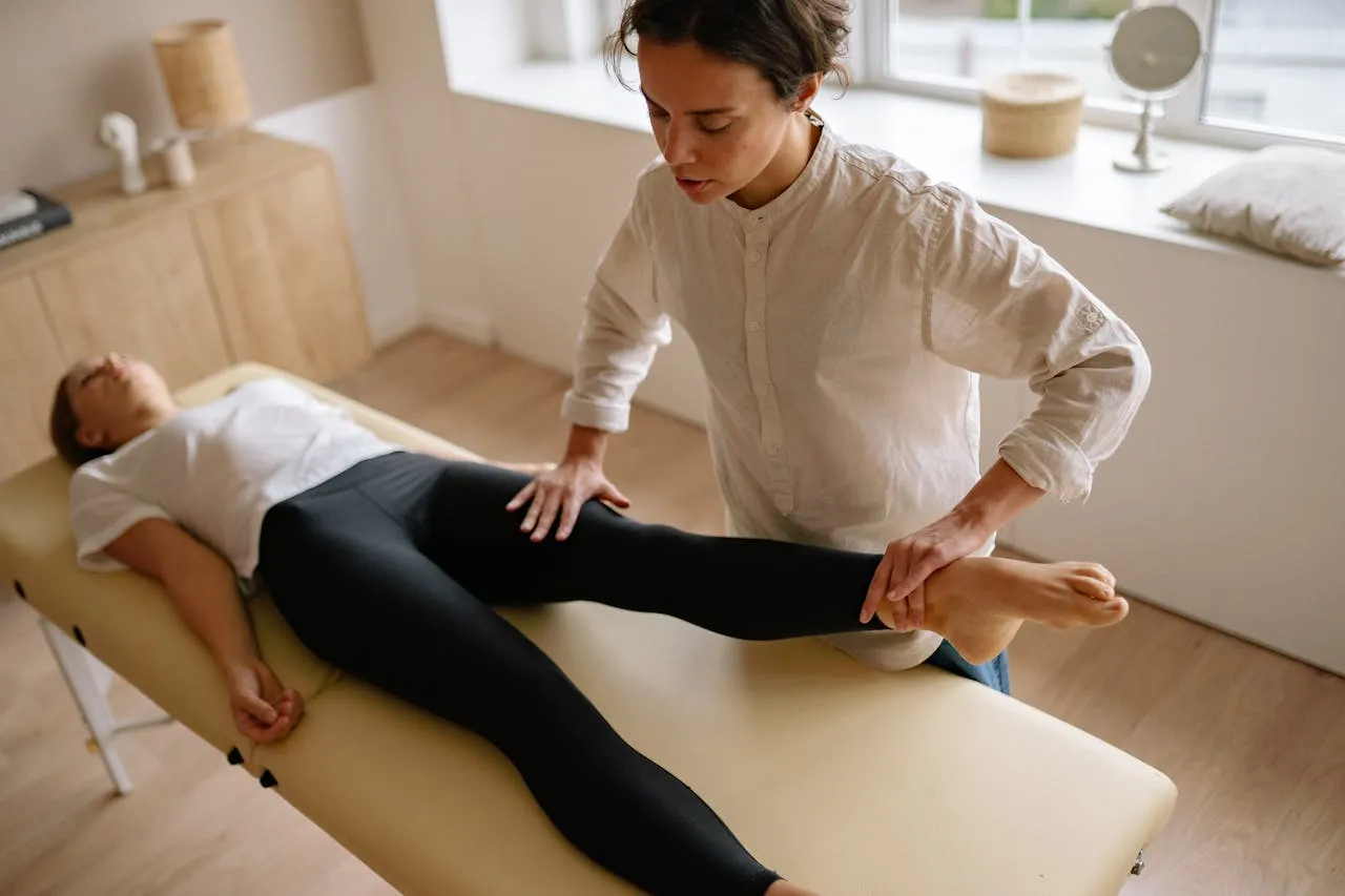 Physical therapist guiding a patient through a gentle back strengthening exercise on a mat in a clinical setting